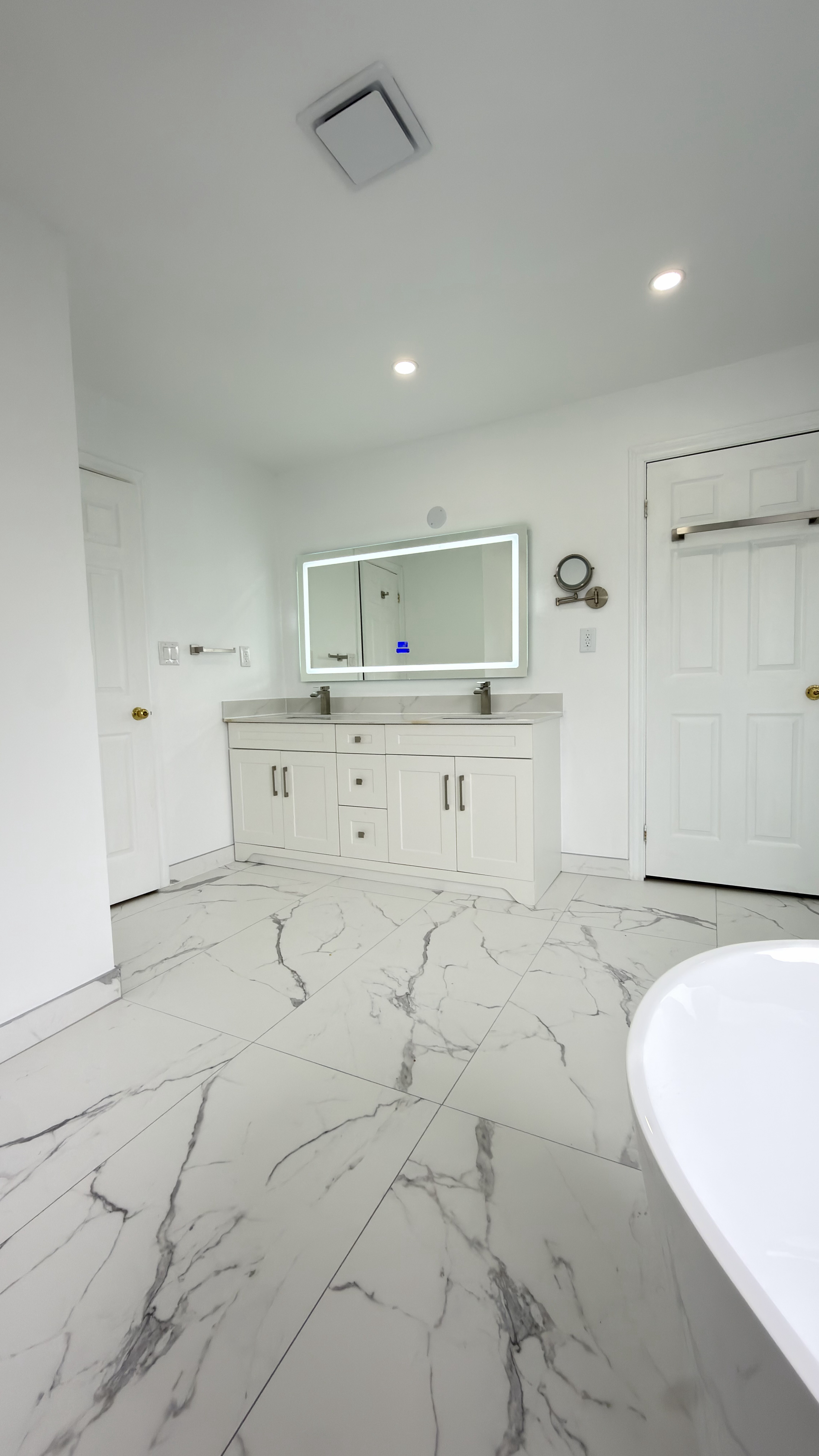 Spacious primary bathroom with marble floors and double vanity